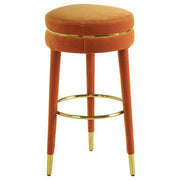 Side view of orange velvet bar stool with gold finish footrest