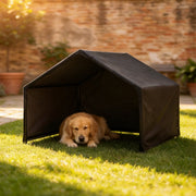 Golden retriever lying inside the black dog shelter on a lawn beside a brick wall