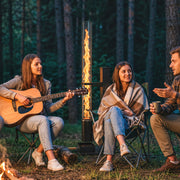 Friends sitting around the pellet heater with a guitar on a garden evening