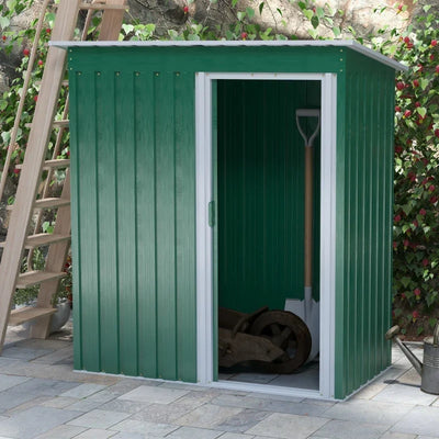 Green shed on a patio with the sliding door open showing a wheelbarrow and spade inside