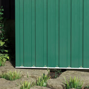 Close-up of the lower green wall panels and base rail where the shed meets the ground