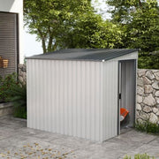 The white metal shed on a patio beside a stone wall and trees with its door slid open