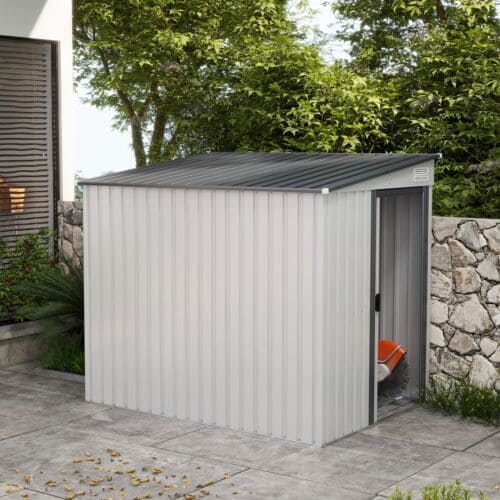 The white metal shed on a patio beside a stone wall and trees with its door slid open