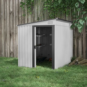 The shed standing on grass against a tall wooden fence with a wheelbarrow visible inside