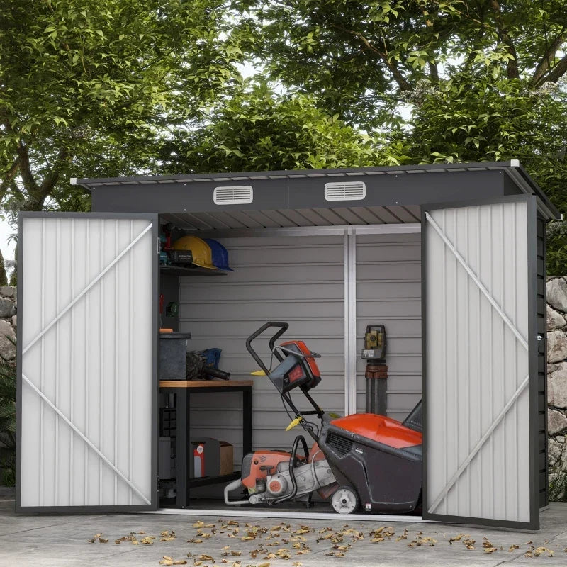 Dark grey shed in a garden with doors open on a workbench, chainsaw and hand tools