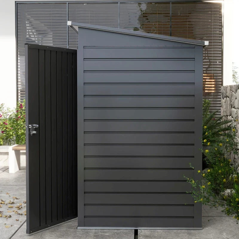 Side view of the dark grey shed beside a house wall showing the pent roof sloping to the back