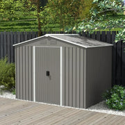 Light grey metal shed on garden decking beside a dark fence and flowering shrubs