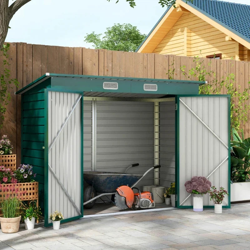 Green shed on a patio with both doors open showing a wheelbarrow and power tools
