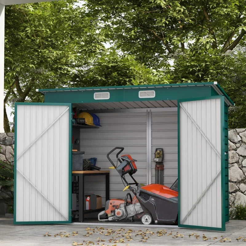 Green shed against a stone wall, doors open on a workbench, mower and hand tools