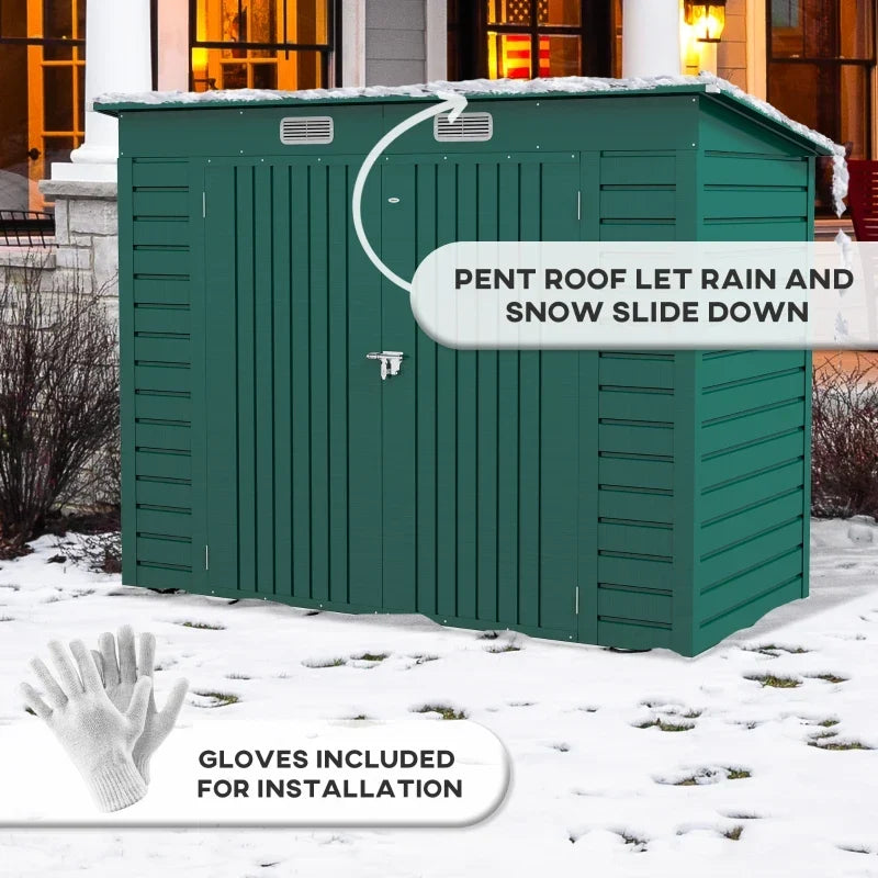 Green shed in snow showing the pent roof shedding snow, with the included safety gloves