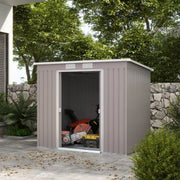 Light grey pent roof shed beside a house wall with one sliding door open, showing a mower and tool boxes inside