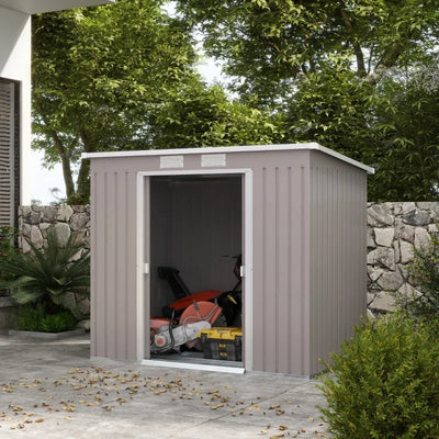 Light grey pent roof shed beside a house wall with one sliding door open, showing a mower and tool boxes inside