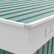 Close-up of the green corrugated roof panels, white eaves trim and a louvred wall vent