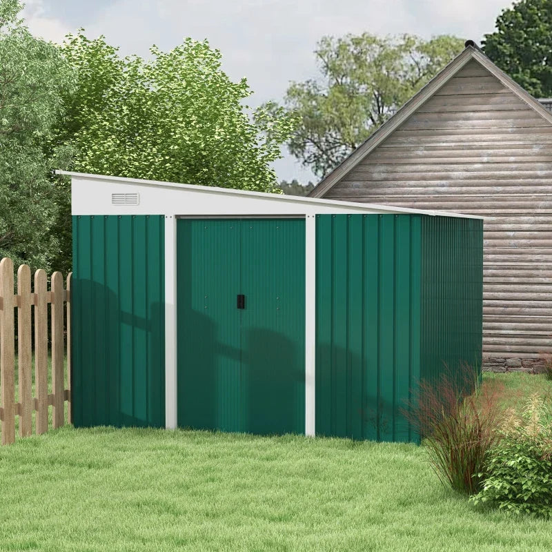 Green lean to metal shed on a lawn beside a picket fence and a timber cabin, doors closed and roof sloping to the front