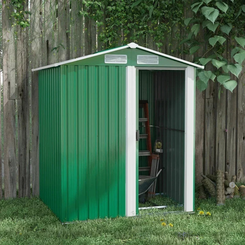 Green metal garden shed against a wooden fence with the sliding door open and tools stored inside