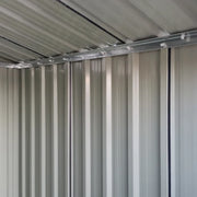 Interior view along the shed's corrugated steel side wall and the rail running under the roof