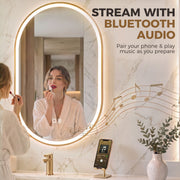 Woman applying lipstick at the oval LED mirror with a phone playing music nearby