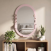 Oval pegboard mirror on a bedroom wall above a bookcase with plants