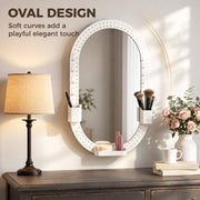 Oval pegboard mirror above a console table beside a lamp and flowers