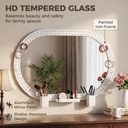 Oval mirror hung sideways above a dresser with tempered glass and painted iron frame callouts