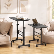 Two black overbed tables set at different heights beside a cream sofa and an armchair