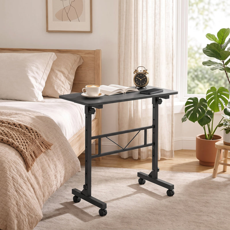 Black overbed table beside a bed with a coffee cup, open book and alarm clock on top