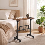 Brown overbed table beside a bed holding a coffee cup, open book and alarm clock