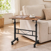 Brown overbed table pulled alongside a cream sofa with a magazine and a cup of coffee