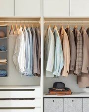Wardrobe interior with shirts and jackets hanging on matching wooden hangers