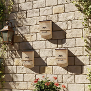 Three PawHut bat boxes mounted on a garden stone wall