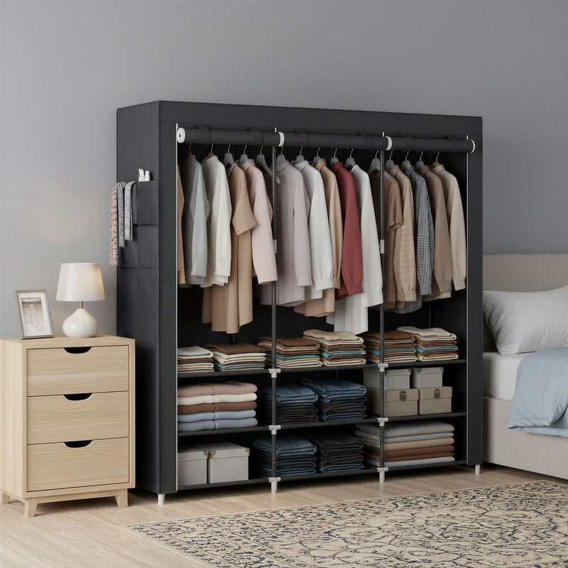 Black fabric wardrobe in a grey bedroom beside a bed and wooden bedside chest