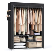 Black portable wardrobe filled with clothes, bags and folded linen on a white background
