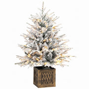 Snow-flocked pre-lit table Christmas tree in a wood-effect base on white
