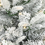 Close-up of snow-flocked branch tips and warm white LED lights