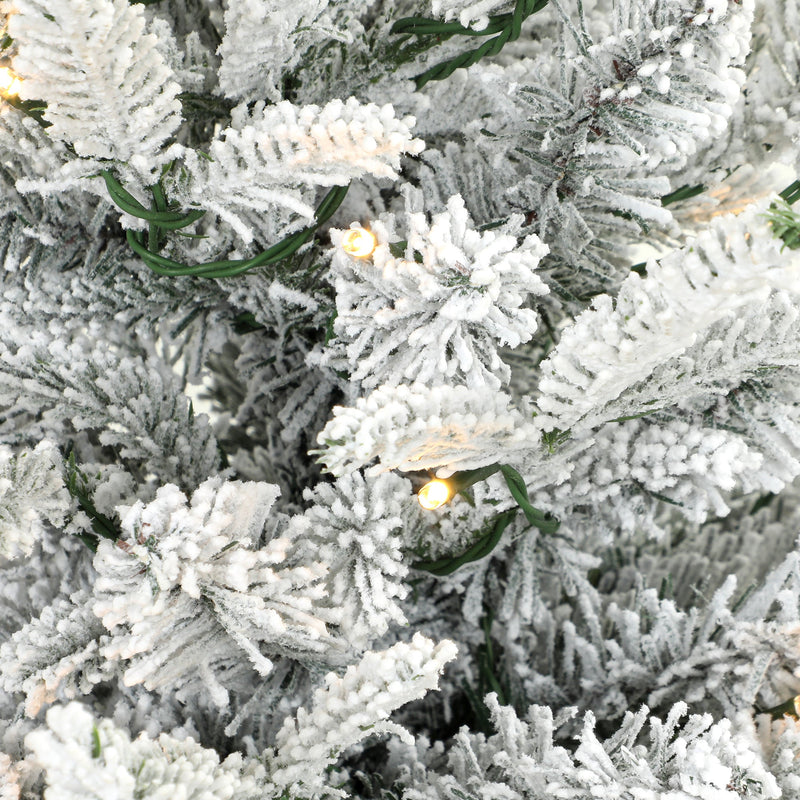 Close-up of snow-flocked branch tips and warm white LED lights