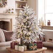 Flocked table tree with wrapped gifts on a coffee table in a living room