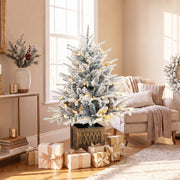 Flocked tree with warm lights on a side table beside a window