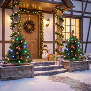 Pair of lit Christmas trees beside a garlanded front door in the snow