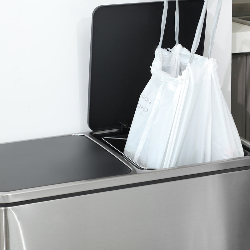 Two white drawstring bin bags fitted inside an open stainless steel double kitchen bin