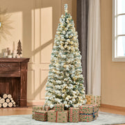 6ft snow flocked Christmas tree lit up in a living room with gifts at the base