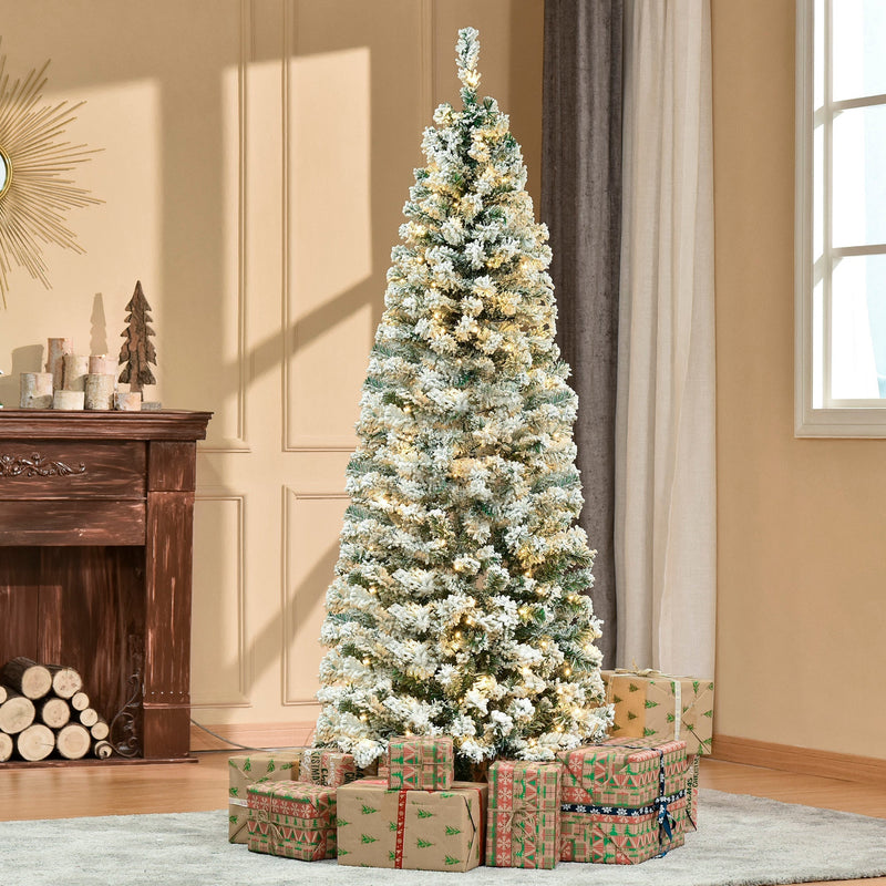 6ft snow flocked Christmas tree lit up in a living room with gifts at the base