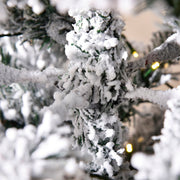 Macro shot of snow flocked branch tips with a string of LED lights on the 6ft tree