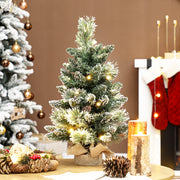 Lit mini flocked Christmas tree on a table beside red stockings and a fireplace
