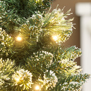 Close-up of snow-flocked branch tips with warm white lights