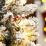 Close-up of snow-flocked branch tips with red berries and warm white lights