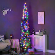 Tall slim pre-lit Christmas tree with multicoloured lights in a purple-lit living room corner