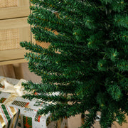 Close-up of green tree branches beside wrapped presents and a wicker cabinet