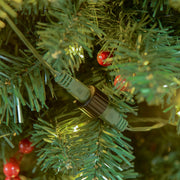 Close-up of the light string connector among green branches and red berries on the 7ft tree