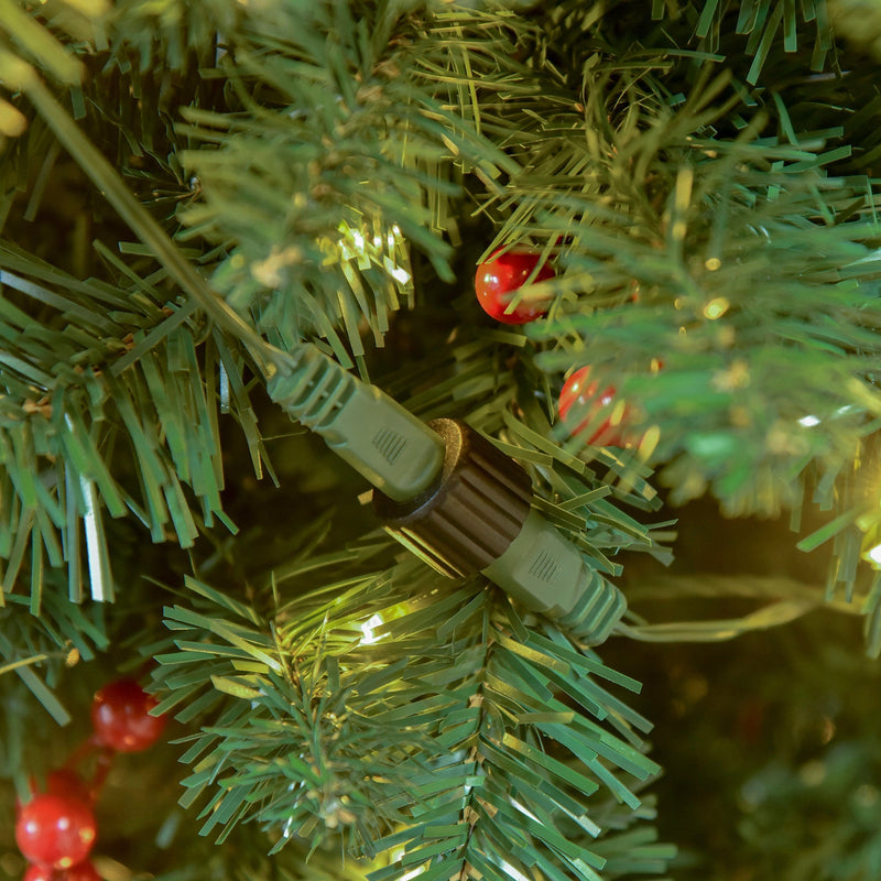 Close-up of the light string connector among green branches and red berries on the 7ft tree