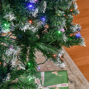 Close-up of green branches with white tips and LED lights beside a wrapped present